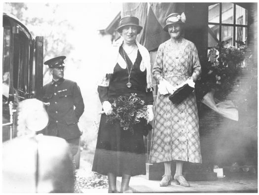 Lady Hilda Garran and Lady Isaacs, wife of the Governor General, standing on the steps of Government House, Yarralumla. A chaffeur is standing by a car.