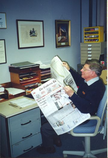 John Farquharson sitting in the CDHS office reading The Canberra Times.