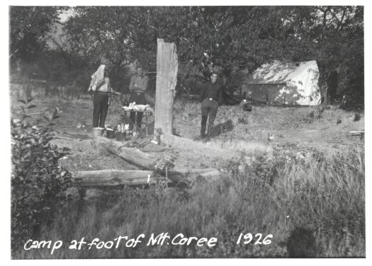 Three men at a camp site at the foot of Mt. Coree