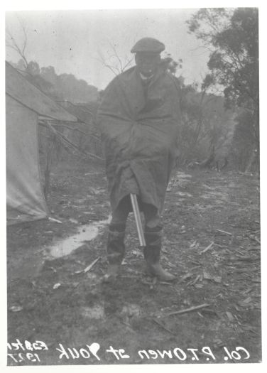 Colonel Owen at Yaouk, Easter 1927, standing in the rain. He is holding a rifle.