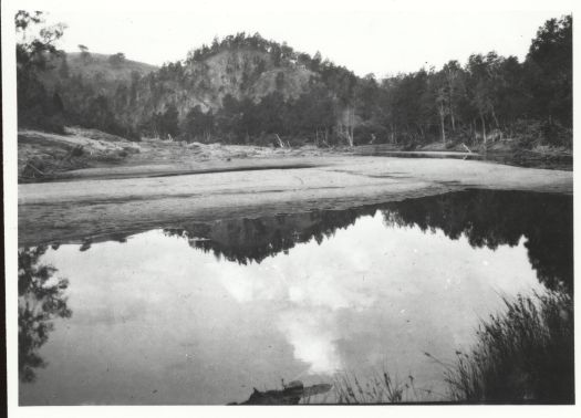 The hills around the river are reflected in the water. The photo is called 'Reflections'.