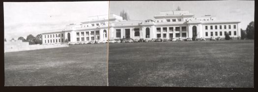 A distant view of Parliament House with two cars parked in front