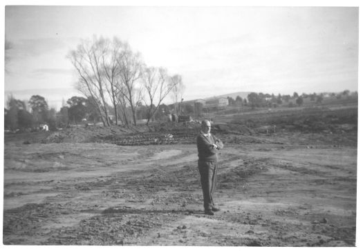 Photo shows Jack Benson standing where East Basin in Lake Burley Griffin now is, from in front of the Power House. The old Riverside buildings in Barton are visible in the background.