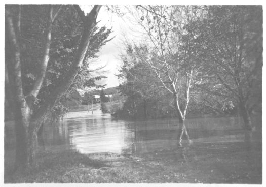 Lennox Crossing (bridge) flooded by the Molonglo River. A building is visible in the background.