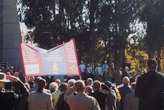View of the crowd and banner of the RAAOC on Anzac Parade.