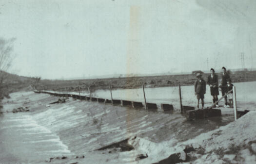 Four children standing on the weir on the Molonglo River below the Power House