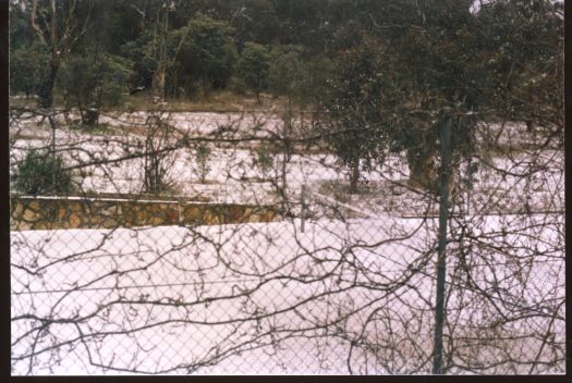 Unidentified scene showing snow through a chain link fence