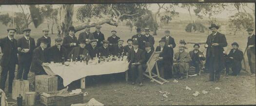 Large format photograph showing Scrivener, Wilson, Moore, Mahon, Knibbs and journalists at a long table near the surveyors camp, Camp Hill, Canberra.