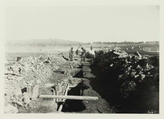 The open trench and formwork with three men working above.