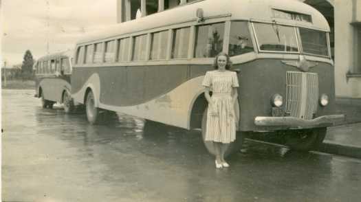 Daphne Tongue standing in front of one of two buses. Probably the Sydney Building on Northbourne Avenue.