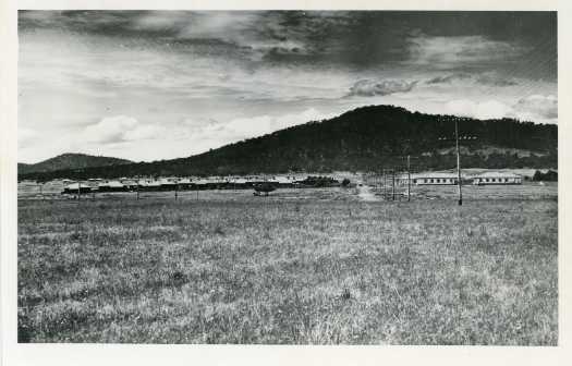 View of Braddon with "Hotel Ainslie" at right and cottages at left. A car can be seen on a dirt road, now Batman Street with Mt Ainslie in the background.