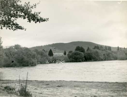 View of a flooded Molonglo River. A two storey building can be seen.