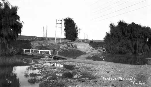 A more distant view than photograph 10169 of the Molonglo River crossing at Acton. In the foreground is a footbridge over the river.