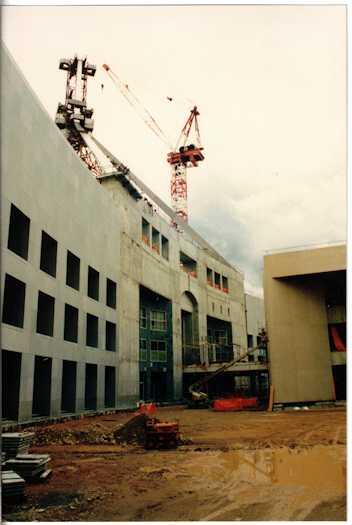 View from the ground of a crane raising a leg of the flagpole