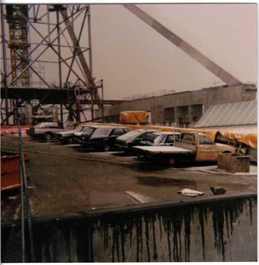 Eight vehicles parked on top of Parliament House. Flagpole leg is visible and a crane.