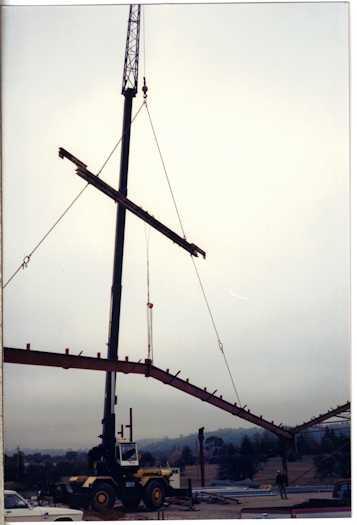Crane lifting a girder watched by a workman