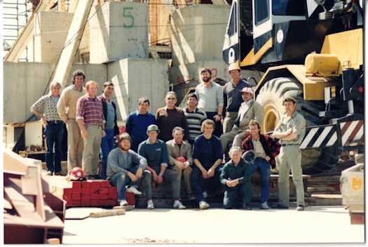 Seventeen workmen involved in building the flagpole posing in front of a crane