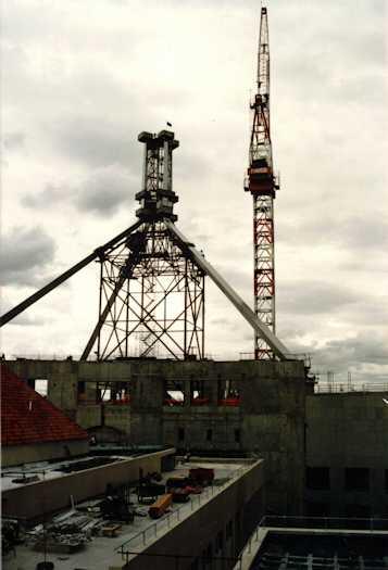 Side view of the partially completed flag pole, surrounded by scaffolding with a crane at right