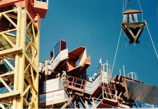 A section of the flag pole being moved into place, watched by workmen