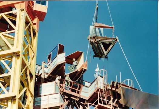 A section of the flag pole being moved into place, watched by workmen