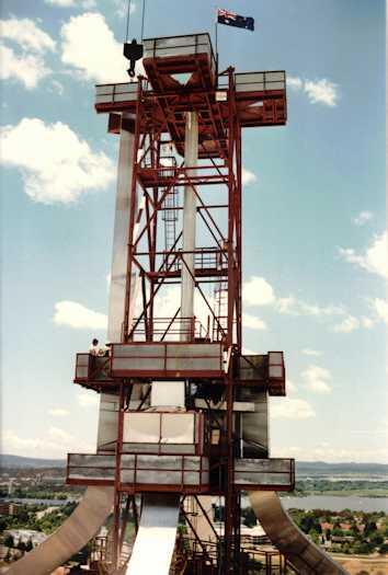 Two workmen on a platform below the mast. Lake Burley Griffin in the background.