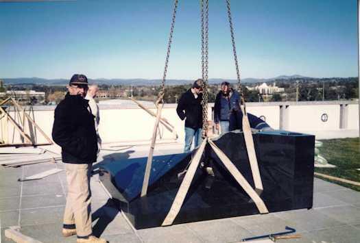 Three workmen, one possibly Alfred Chambers, watching material being lifted