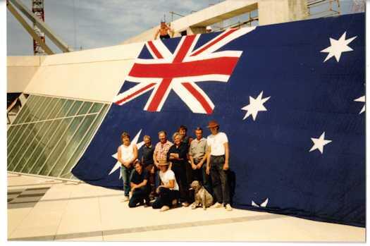 Nine members of the flag mast team in front of the Australian flag. The dog, Two Bob, a bull terrier cross is an honorary rigger.