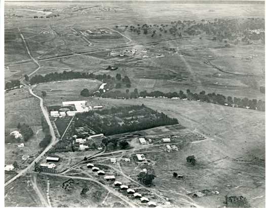 Shows government buildings at Acton, Hotel Canberra and Provisional Parliament House under construction in distance. Weston's experimental plant nursery is clearly visible at centre.
