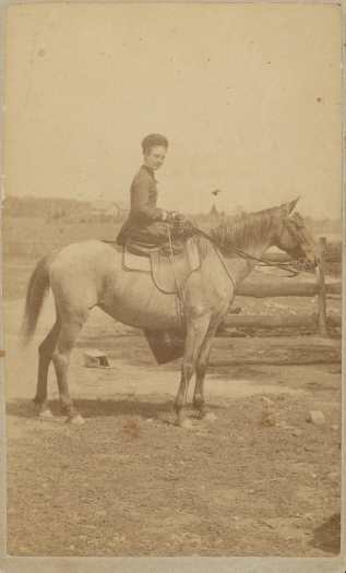 Margaret is sitting side saddle on a horse.