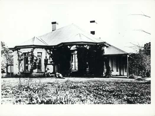 Two large bay windows and three men standing and sitting at front.