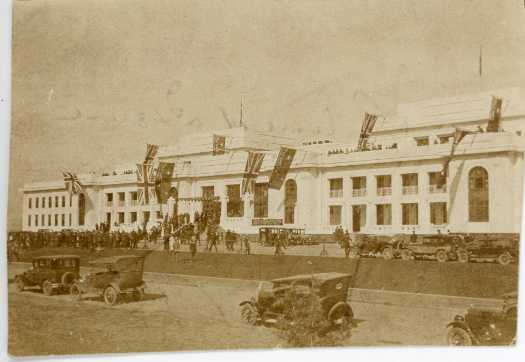 The provisional parliament house decorated with flags. Cars and people in foreground.