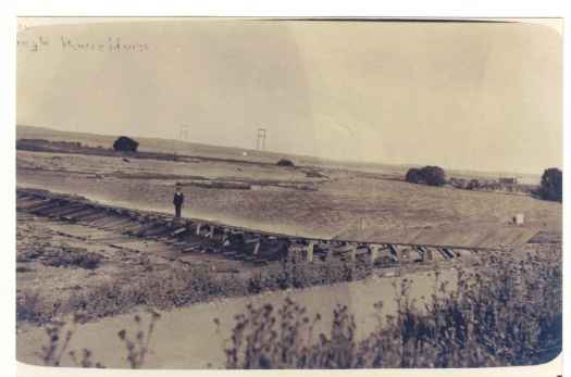 Man standing on what appears to be the light rail track crossing the river.