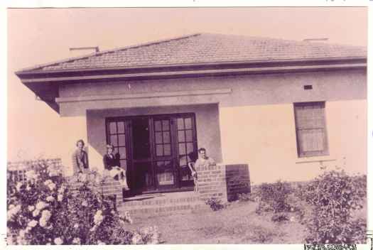 Benson house.Three people on the verandah at front.