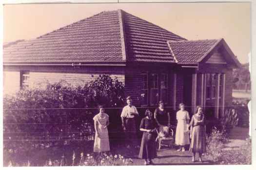 Front of house with group of 5 women and one man standing outside. See notes.