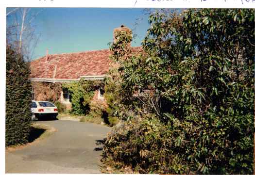 Shows car parked in driveway and well-established garden.