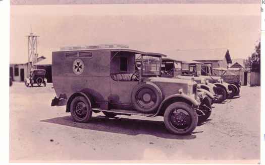Back of photo reads: The first ambulances -part of the fire Station at back of the Power House in 1920s. Harold Strachan drove an ambulance when he first became a Commonwealth driver. At right rear the roof of the Saunder family house and their back gate.