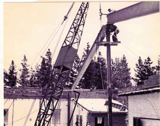 Crane lifting beams into place and two dogmen.