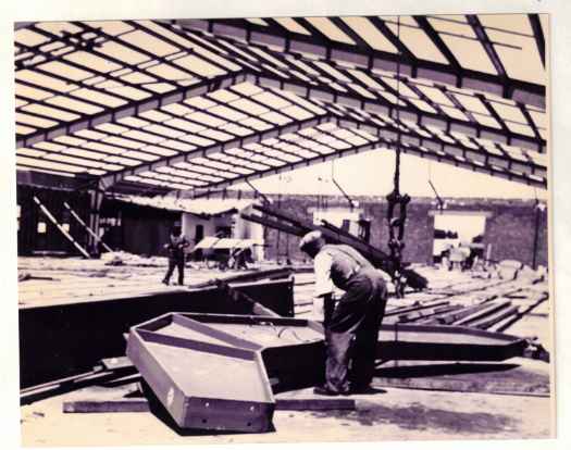 Taken from inside the site. Man shown bending over very large metal component.