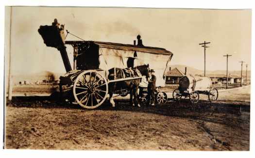 Steam shovel and water tank. Dray with horse alongside. Houses in background.
