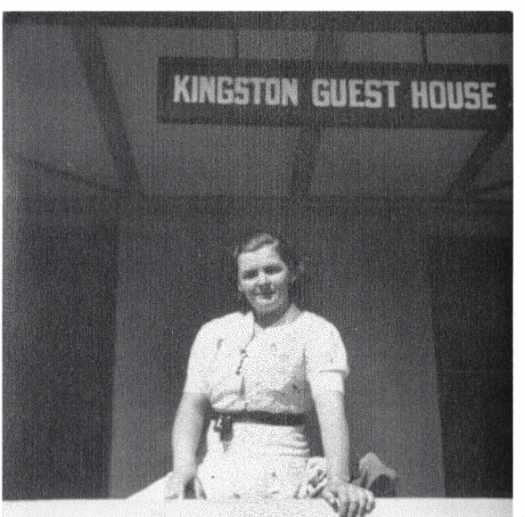 Myrtle is standing under the Kingston Guest House sign.