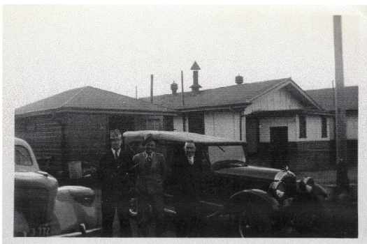 Three people standing in front of a car.