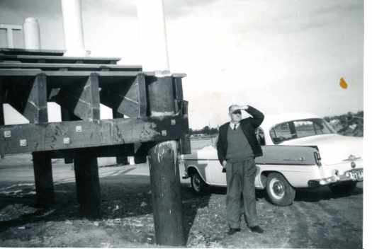 Jack is standing in front of the wharf and his car is beside him, high and dry.